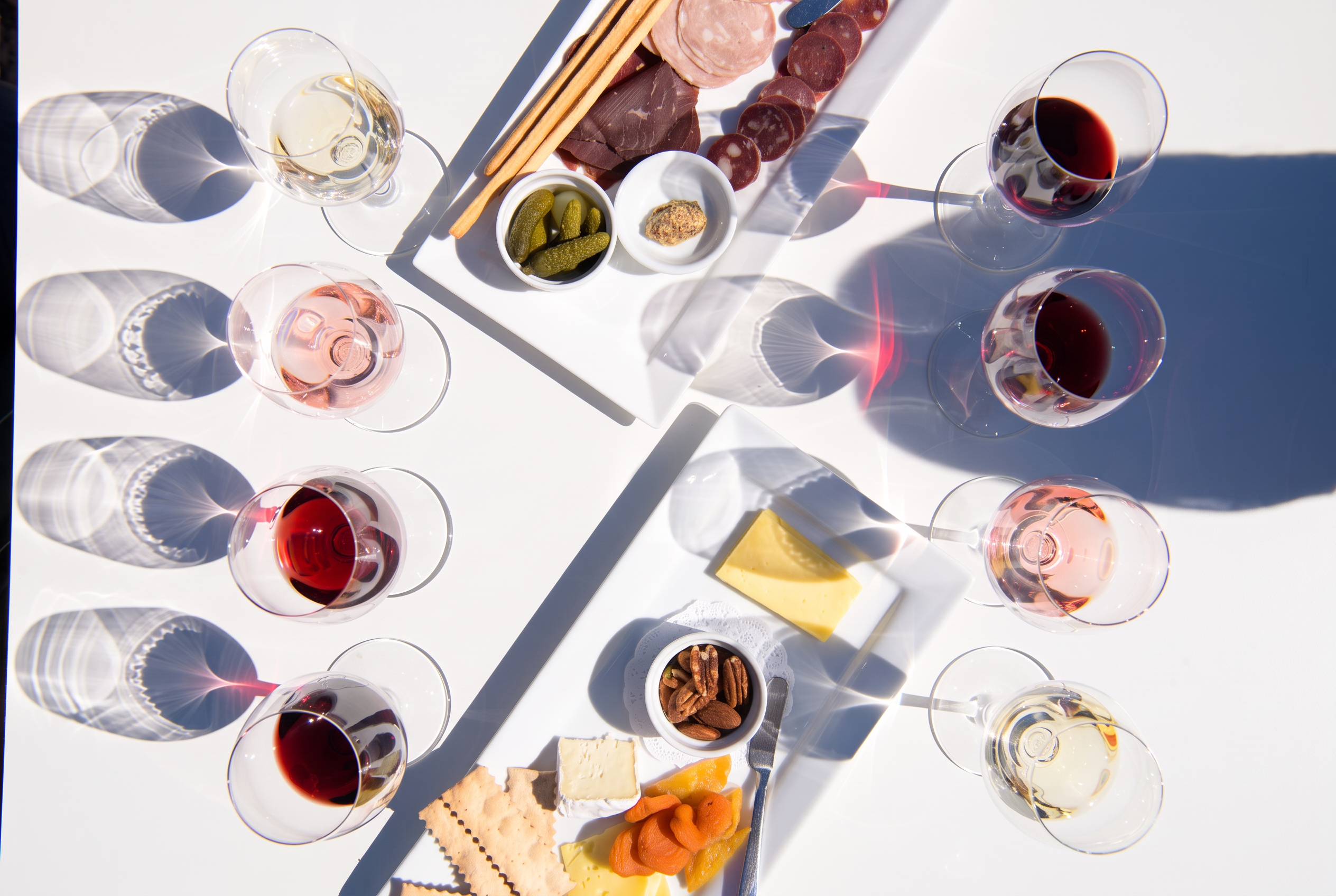 An overhead spread of wine glasses with charcuterie, cheese and accompaniments